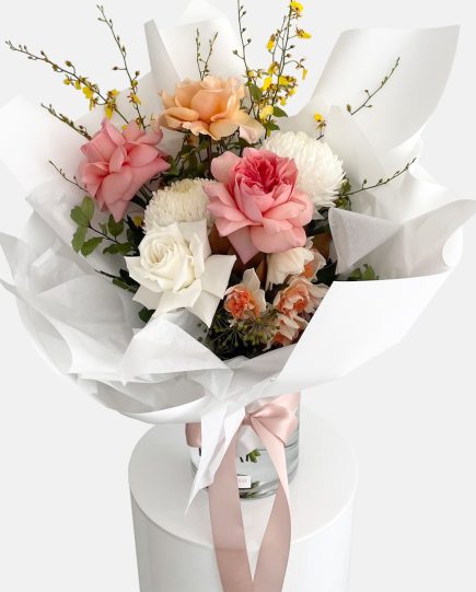 A colourful bouquet of flowers in peach, lemon tones, roses, disbud chrysanthemum, oncidium orchids and daffodils. Designer Bouquet for same day flower delivery Gold Coast